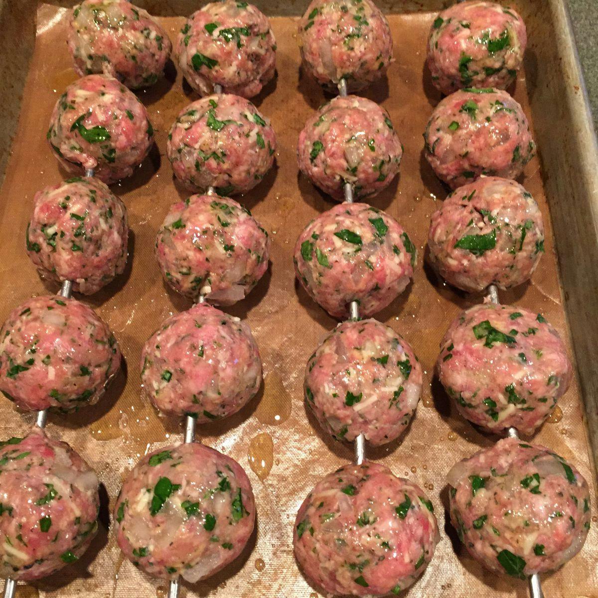 Raw meatballs skewered on a pan with contact paper - Grilled meatballs recipe